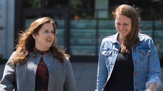 Two people walking towards the camera, they look like they are having a conversation