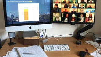 A desk with a computer, keyboard, and notepad. The screen has a charts and graphs on it.