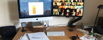 A desk with a computer, keyboard, and notepad. The screen has a charts and graphs on it.