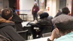 A group of people at Webber Street Day Centre, looking towards someone leading an activity