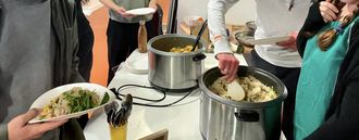 A table with two pots of food on it. Hands are serving food from the pots.