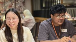 Four people sit around a table in conversation with one another.