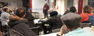 A group of people at Webber Street Day Centre, looking towards someone leading an activity
